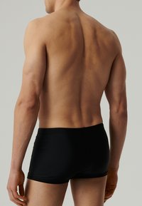 Czarne szorty kąpielowe, gładki materiał, dopasowany krój, długość do połowy uda, elastyczny pas, minimalistyczny styl bez widocznego logo.