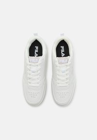 White athletic shoes with a leather-like exterior, round toe, lace-up closure, perforated detailing, and black insoles featuring the brand logo.
