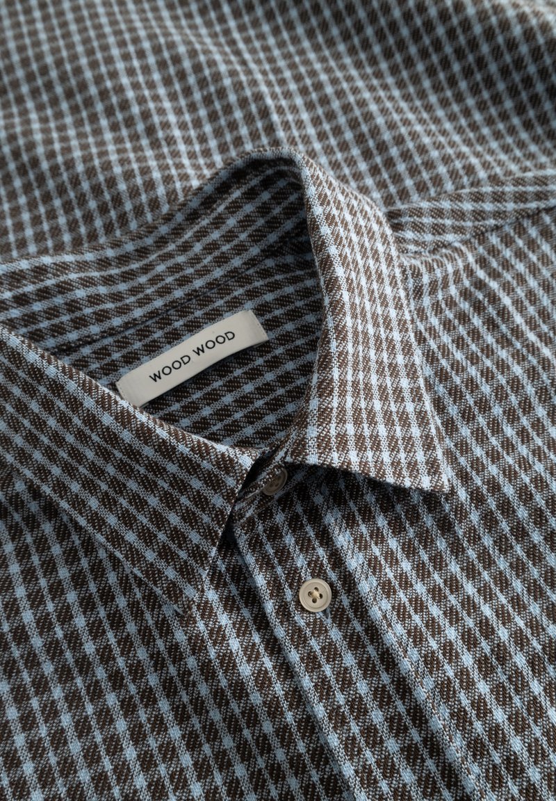 Buttoned brown and light blue checkered shirt collar with a visible "WOOD WOOD" brand label inside the collar.