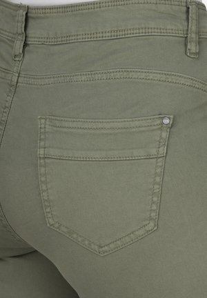 Olivgrüne Denim-Jeans mit einem Nahaufnahme des hinteren Taschens, die subtile Nähte und ein metallisches Nieten-Detail aufweisen. Weiche Textur und taillierter Schnitt.