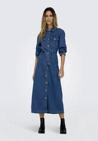 Vestido de ganga com um design de frente com botões, mangas longas e um laço na cintura. Apresenta dois bolsos no peito e uma silhueta A-line de comprimento médio. Cor azul escura.