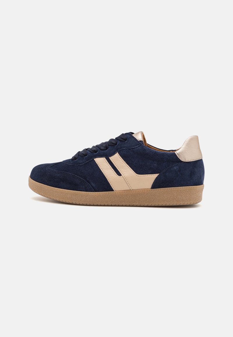 Baskets en daim bleu marine avec des accents en cuir beige, semelle en gomme beige et lacets noirs, vues de côté extérieur sur fond blanc.