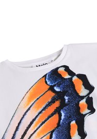 Camiseta blanca de manga corta con un gran gráfico de ala de mariposa colorido en naranja, azul y negro. Cuello redondo, material de algodón suave.