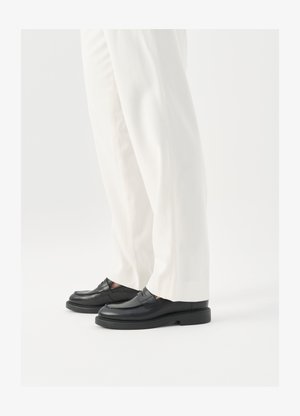 Sorte læder loafers med en glat overflade, syninger og en rund tå, parret med hvide skræddersyede bukser.
