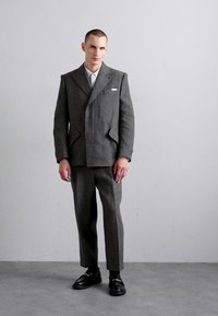 Hall gray villane suit, millekergiga jack, millelõigatud kraed ja kohandatud püksid. Sile tekstuur, minimalistlik disain ja peened taskute detailid.