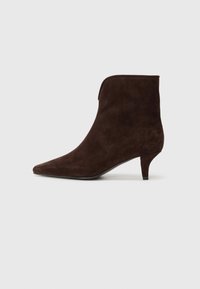 Bottine en daim marron avec un bout pointu, un talon fin et un design supérieur sans couture. Texture lisse et détails minimaux.