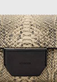 Borsa a pochette in pelle di serpente con un motivo testurizzato oro e nero, con un accento in pelle nera e dettagli con logo stampato.