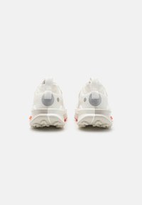 Witte sportieve schoenen met een gestructureerde bovenkant, voorzien van grijze accenten en een opvallende zool met felle rode highlights. Trekhaak aan de hiel.