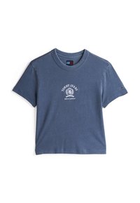 Zila kokvilnas T-krekls ar apaļu izgriezumu, īsām piedurknēm un baltu grafiku ar uzrakstu "TOMMY JEANS EST. 1985" priekšpusē.