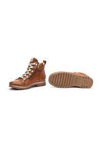 Brown leather ankle boots with a zipper, gold eyelets, and textured sole. Features a rugged design and flexible, cushioned construction.