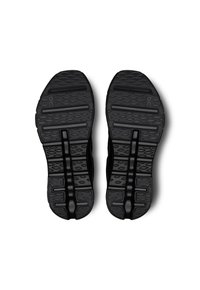 Des chaussures de sport noires présentent une semelle extérieure en caoutchouc texturé avec un motif géométrique pour l'adhérence et la flexibilité. Aucun autre détail n'est visible.