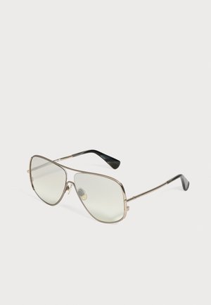Lunettes style aviateur à monture métallique avec verres légèrement teintés et embouts incurvés noirs sur fond blanc.