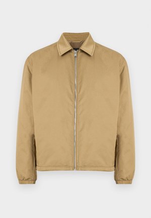 Béžová bunda na zip s texturovaným povrchem, špičatým límcem, elastickými manžetami a bočními kapsami. Vyznačuje se jednoduchým, minimalistickým designem.