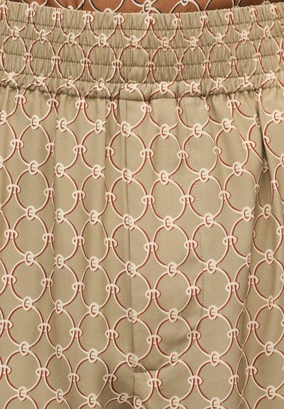 Tissu beige avec un motif répétitif de chaînes géométriques en crème et rouille, doté d'un fronces élastique sur le bord supérieur.