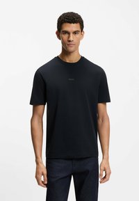 Czarny T-shirt z krótkim rękawem, z okrągłym dekoltem i subtelnym logo "BOSS" na środku. Wykonany z gładkiej tkaniny, o luźnym kroju.