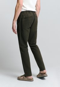 Donker olijfgroene taper-pants van katoen, met een elastische tailleband, zijzakken en een zachte textuur.