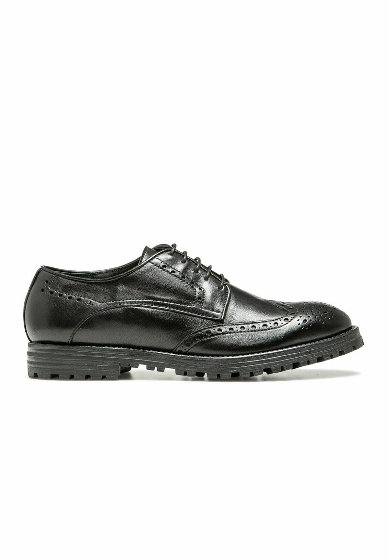 Chaussure brogue en cuir noir avec des perforations, fermeture à lacets, bout rond et semelle en caoutchouc pour l'adhérence et la durabilité.