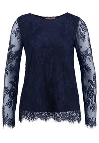 Top in pizzo blu navy con maniche lunghe trasparenti, motivo floreale, orlo scalloppato e scollatura tonda. Texture morbida, decorata con intricati lavori in pizzo.
