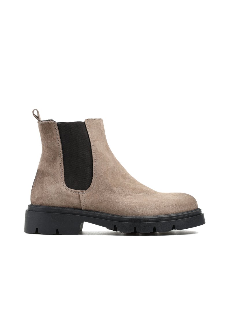Brązowe zamszowe botki typu Chelsea z czarnymi elastycznymi panelami bocznymi, pętelką do zakładania i masywną czarną gumową podeszwą o teksturowanym wykończeniu.