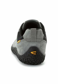 Grau Wildlederschuh mit schwarzer Gummisohle, strukturiertem Grip, Mesh-Akzenten, Zuglasche und gelben Details an der Seite, von hinten betrachtet.