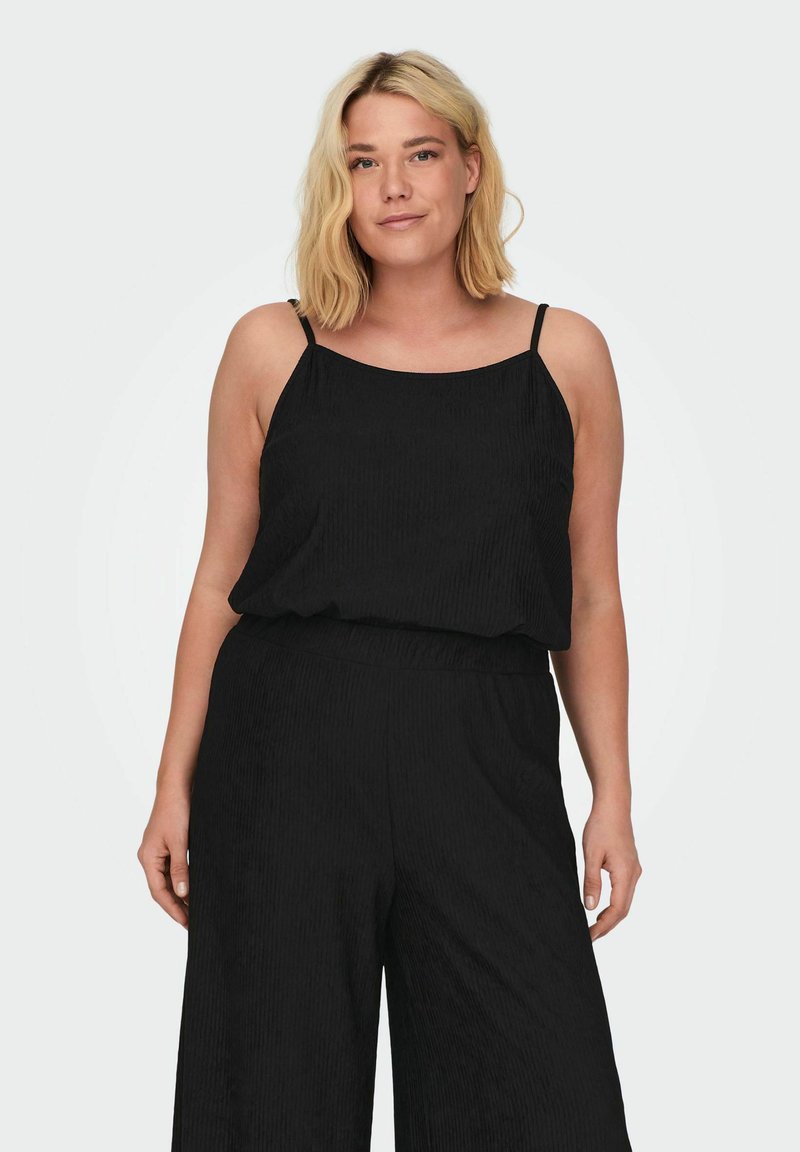 Must mustriba õhuke rihmadega must tank top, ribakujuline tekstuur ja lõdva istuvusega. Kombineeritud laia jalaga mustade pükstega, millel on elastne vöökoht.