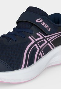 Αθλητικό παπούτσι ASICS σε ναυτικό μπλε με ροζ λογότυπα, λουράκι με βέλκρο, ναυτικό μπλε κορδόνια και λευκή σόλα με ροζ περίγραμμα.