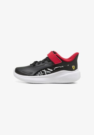 Baskets pour enfants noir et rouge avec semelle blanche, lacets noirs, une bride rouge, un motif abstrait sur le côté, et un petit logo Ferrari jaune sur le talon.