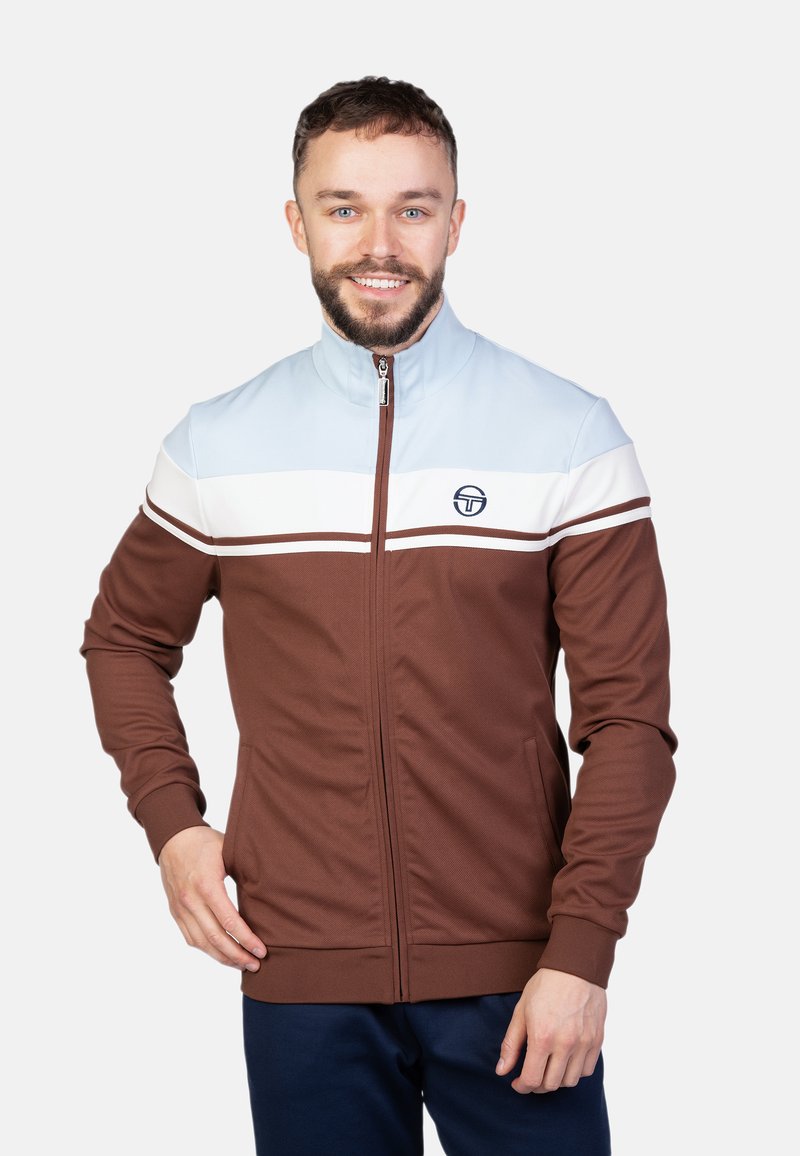Bruine zip-up jas met een hoge kraag, voorzien van lichtblauwe en witte horizontale strepen over de borst en een logo aan de linkerkant.