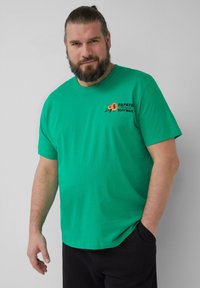 Groene katoenen T-shirt met korte mouwen, voorzien van een kleurrijk "Papaya" surfwax-logo op de linkerborst. Soepele textuur en casual pasvorm.