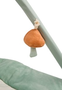 Soft green fabric with a plush texture; a hanging orange mushroom toy features a striped stem and a beige loop for attachment.