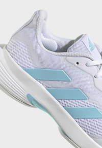 White athletic shoe with mesh fabric, featuring light blue accents and three blue stripes on the side. Textured sole for grip.