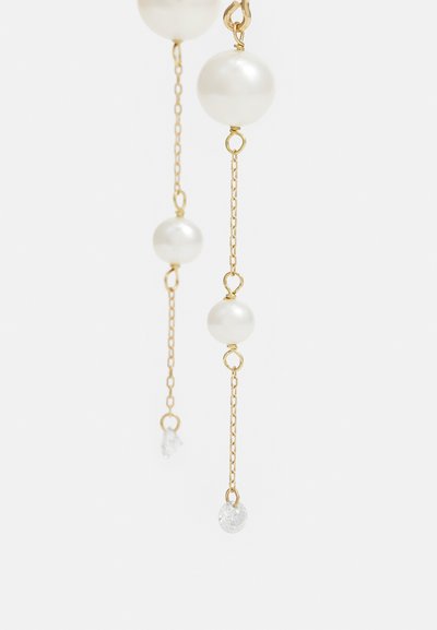 Kultaiset korvakorut, joissa roikkuvat valkoiset helmet ja kirkkaat kristallikoristeet hennolla ketjulla. Tyylikäs muotoilu ja sileät pinnat.