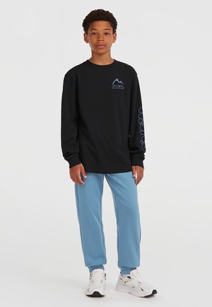 Svart långärmad skjorta med blå logotyp, parat med ljusblå sweatpants och vita sneakers, med elastiska manschetter vid anklarna.