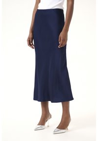 Jupe midi en satin bleu marine avec un léger flare à l'ourlet, présentant une texture lisse et une taille élastique, associée à des escarpins argentés.