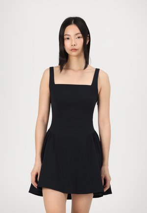 Black dress with a square neckline, wide straps, fitted bodice, and flared skirt. Made of smooth fabric, features a hem that grazes mid-thigh.