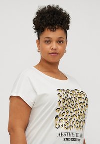 White short-sleeve t-shirt with a gold and black leopard print graphic on the front, featuring the text "AESTHETIC ART 2ND EDITION."