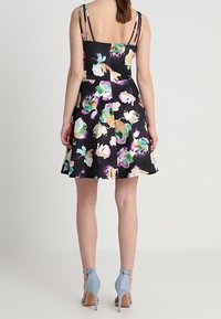 Květinové šaty s přiléhavým korzetem a nabíranou sukní. Černá látka s vícebarevnými květinovými motivy. Tenké, nastavitelné ramínka a rozšířený lem.