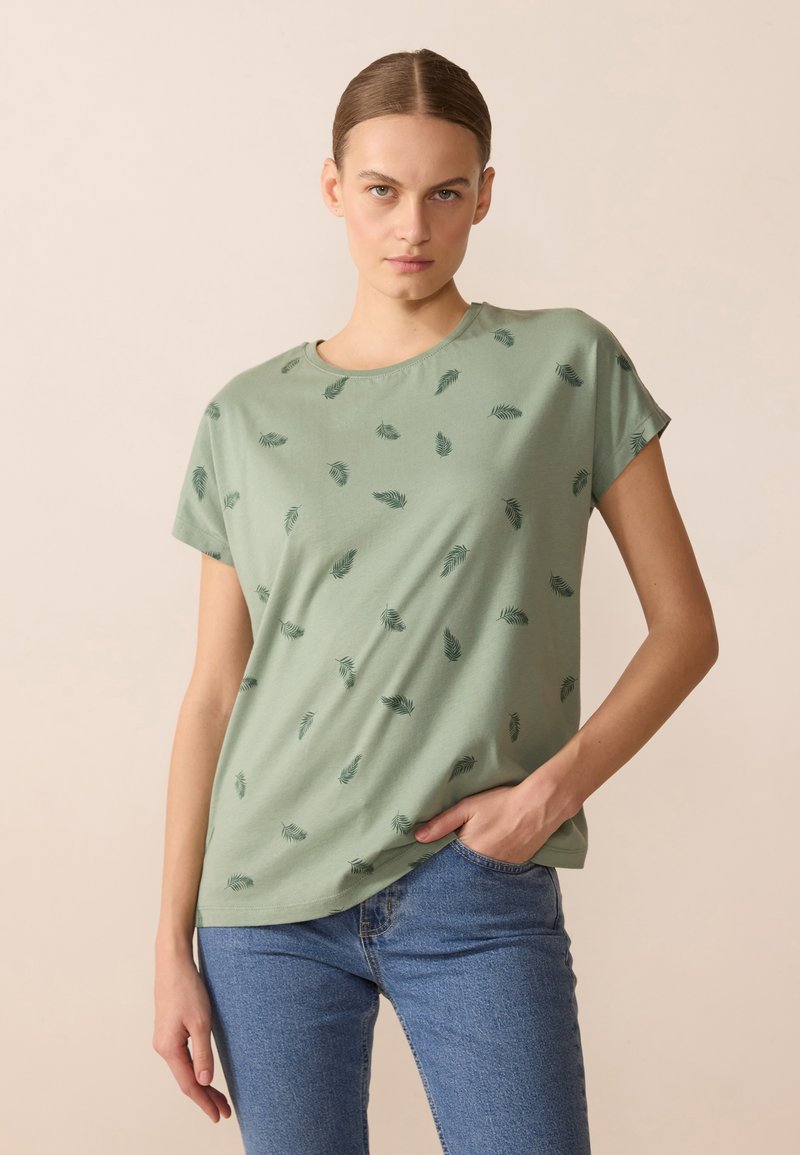 Ljust grön T-shirt med kort ärm som har ett spritt bladmönster i mörkgrön. Mjuk material med rund halsringning och avslappnad passform.