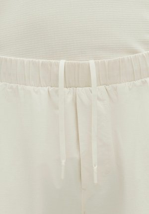 Vaaleanbeiget housut, joissa on teksturoitu kangas, elastinen vyötärönauha kiristysnarulla ja hillitty pystykuvio. Sileä, rento muotoilu.