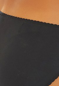 Parte inferior de bikini negra hecha de una tela suave con corte clásico, que presenta una cintura elástica delgada y sin patrones ni herrajes visibles.