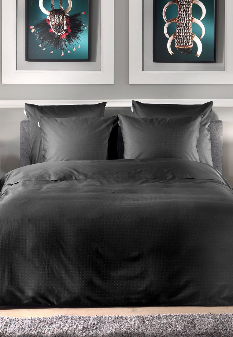 Dunkelgraues Bettwäscheset mit glatter Textur, das mit einem dezent gemusterten Bettbezug und passenden Kissenbezügen auf einem grauen Bettgestell versehen ist.
