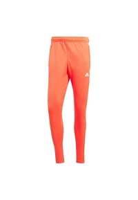 Pantalons de sport orange avec une coupe ajustée, ceinture élastique et logo Adidas blanc sur la cuisse gauche. Tissu lisse et extensible pour un confort optimal.