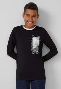 Zwart langwerpig t-shirt met een witte ronde hals, voorzien van een grafische print in wit en geel op de voorkant, met een relaxte pasvorm.