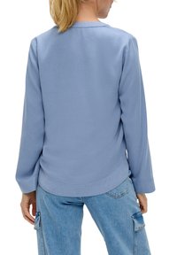 Hellblaues Langarmhemd mit rundem Ausschnitt, glatter Textur und abgerundetem Saum, kombiniert mit hellblauen Cargo-Hosen.