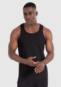 Schwarzes Baumwoll-Tanktop mit Rundhalsausschnitt und weiten Armausschnitten, das ein figurbetontes Design und minimale Nähte für eine glatte Optik bietet.