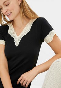 Top nero a maniche corte con scollo a V, caratterizzato da un bordo in pizzo color crema attorno al collo e alle maniche, tessuto morbido e una vestibilità comoda.