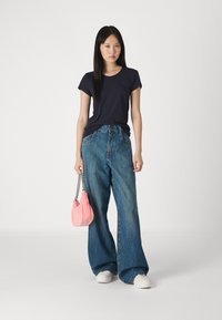 Ναυτικό μπλουζάκι, χαλαρή εφαρμογή, κοντά μανίκια; ανοιχτό μπλε φαρδιά τζιν παντελόνια; ροζ σακίδιο με κορδόνι και αλυσίδα; λευκά αθλητικά παπούτσια.