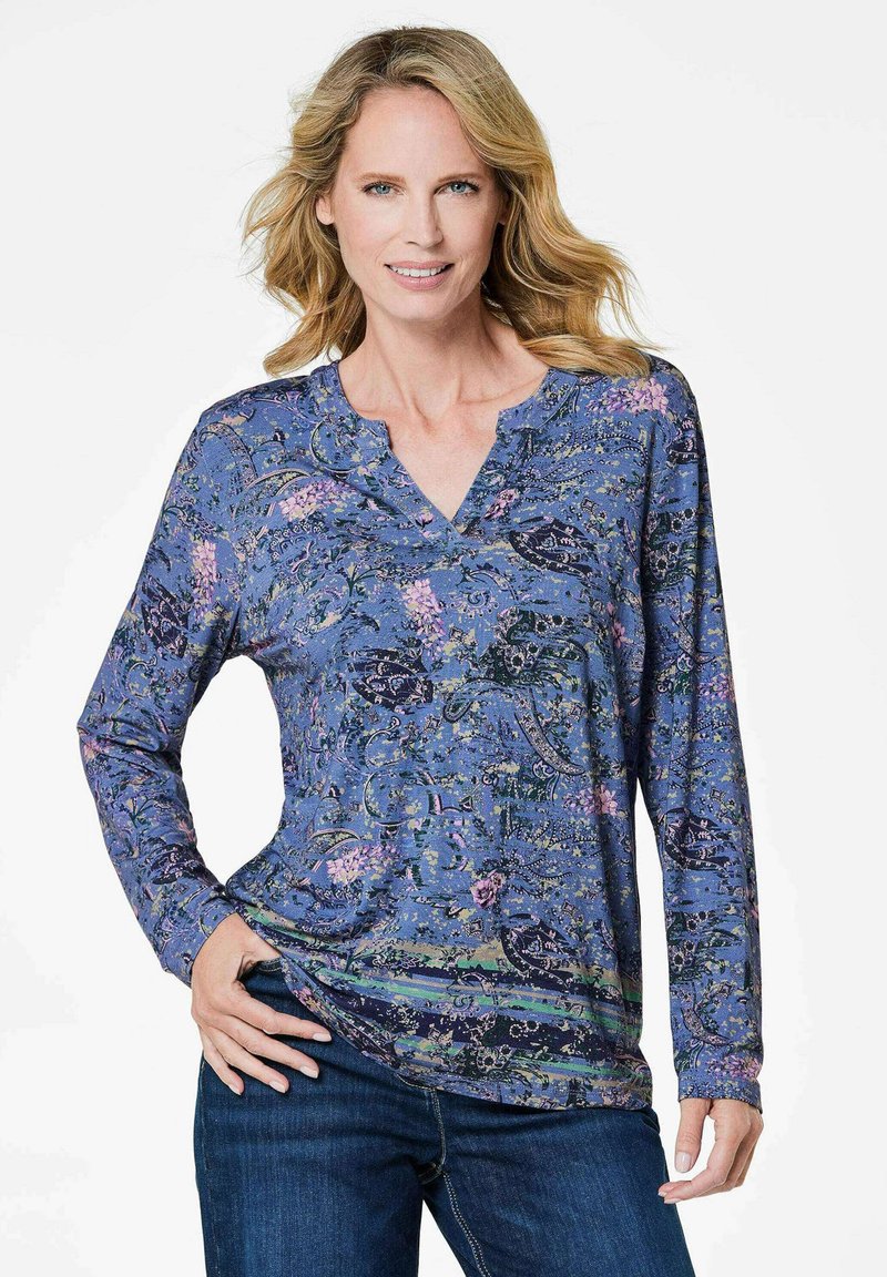 Langärmliges blaues Oberteil mit einem floralen Muster, das eine V-Ausschnitt und eine lockere Passform aufweist. Weicher Stoff mit verschiedenen grünen und pinken Akzenten.