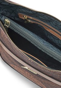 Sac à main marron à motifs avec une fermeture éclair dorée ouverte, révélant un intérieur en tissu sombre et plusieurs compartiments zippés.