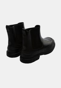 Stivali Chelsea in pelle nera con pannelli elastici sui lati e suola in gomma lavorata con rilievi. Presenta un dettaglio circolare del logo sul tallone.